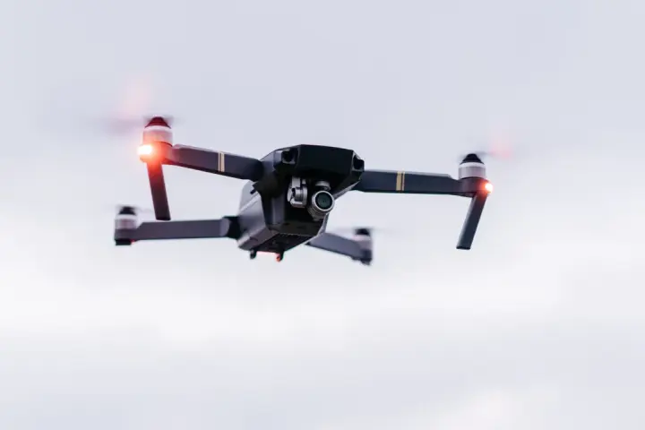 A drone hovers in the sky, its red lights blinking. Planning a trip? Be aware of Bahamas drone laws before you fly.