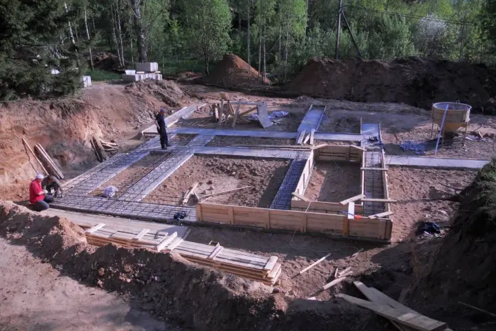 Budowa fundamentów domu. W wykopie widać zbrojenie i szalunki. Pracownicy przygotowują teren pod betonowanie. To będzie solidny chudziak!