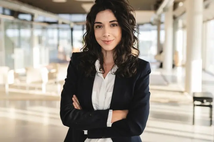 Kobieta w marynarce i białej koszuli, idealnie wpisująca się w **business casual dress code**, pewnie patrzy w obiektyw.