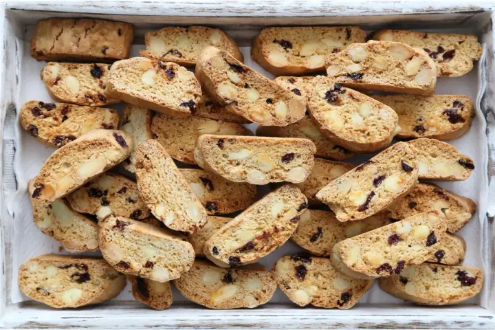 Un vassoio pieno di croccanti biscotti toscani, ricchi di mandorle e mirtilli rossi, pronti per essere inzuppati.