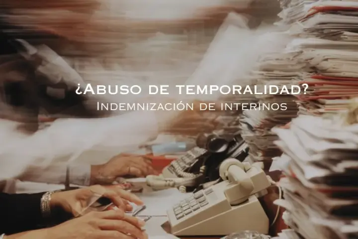 ¿Abuso de temporalidad? Indemnización de interinos tras 3 años. Escritorio caótico con papeles y teléfonos.