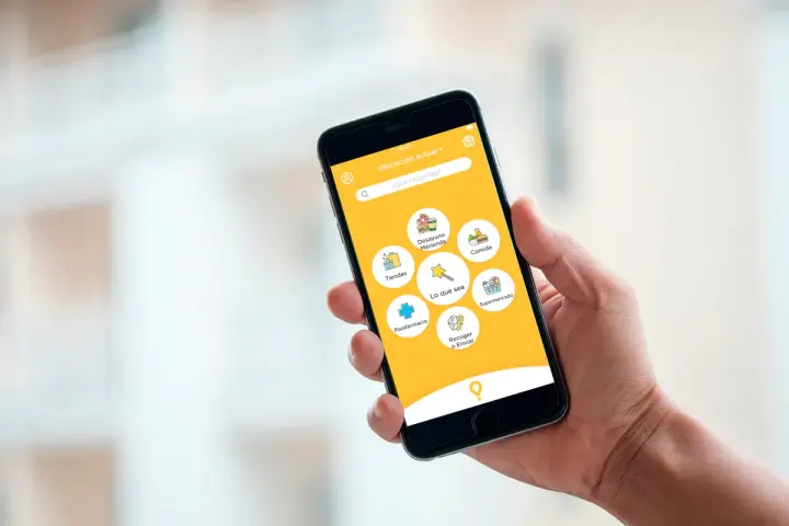 Mano sujetando un smartphone con una app de entregas. Muestra opciones como "Comida", "Supermercado" y "Parafarmacia". Así funciona "just eat".