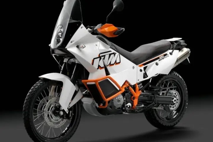 Biały motocykl KTM 990 Adventure z pomarańczowymi akcentami, gotowy na każdą przygodę.