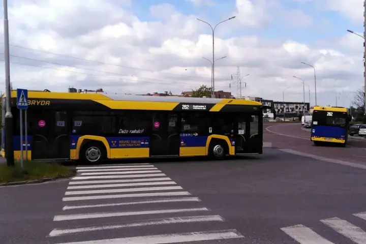 Autobus 262 z napisem "Dużo radości!" zbliża się do przejścia dla pieszych. Sprawdź autobus 136 rozkład jazdy.