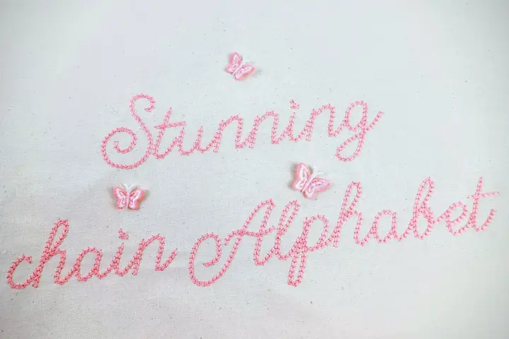 Punto ricamo per scritte: "Stunning chain Alphabet" in rosa, con piccole farfalle applicate.