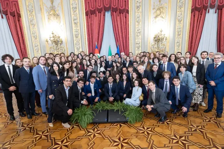 Un folto gruppo di giovani studenti posa per una foto di gruppo, forse dopo un evento alla scuola di giornalismo Roma.