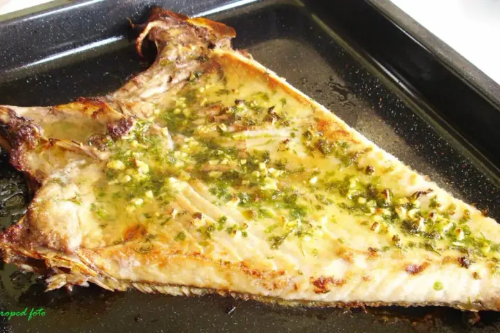 Deliciosa ventresca al horno, dorada y jugosa, con un aderezo de ajo y perejil que invita a probarla.