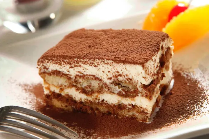 Pyszne tiramisu Ani Starmach, posypane kakao, z owocami i wisienką. Idealne na deser.