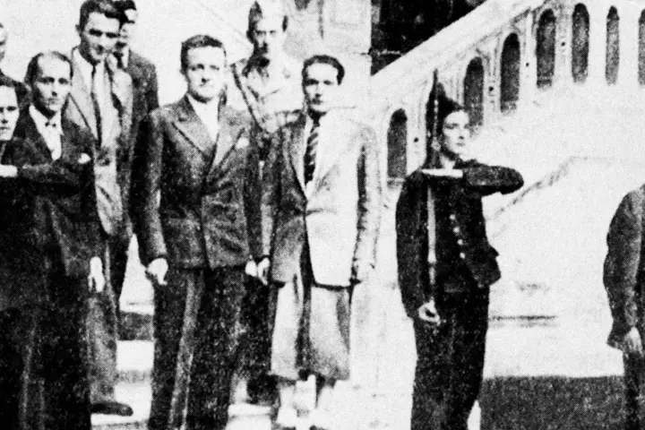 Groupe d'hommes en costume, dont Henri Frenay et François Mitterrand, posant devant un escalier.