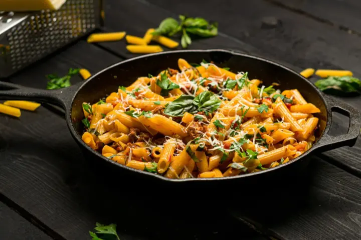 Makaron penne z mięsem mielonym i ziołami w żeliwnej patelni.