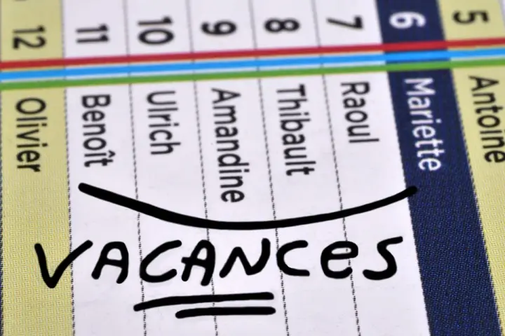 Calendrier avec noms et le mot "VACANCES" écrit à la main.