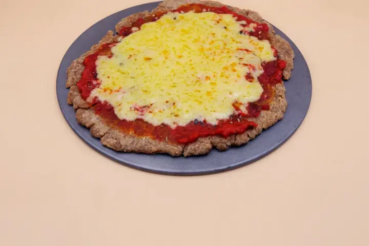 Pizza z chleba tostowego z sosem pomidorowym i roztopionym serem na ciemnej tacy.