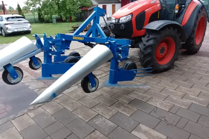 Niebieska kosiarka do fasoli marki SOCHMET, zamontowana z tyłu czerwnego traktora Kubota, gotowa do pracy na polu.