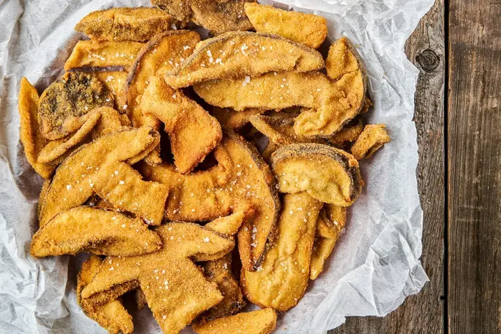 Un cesto pieno di croccanti funghi fritti, cosparsi di sale grosso, pronti per essere gustati.