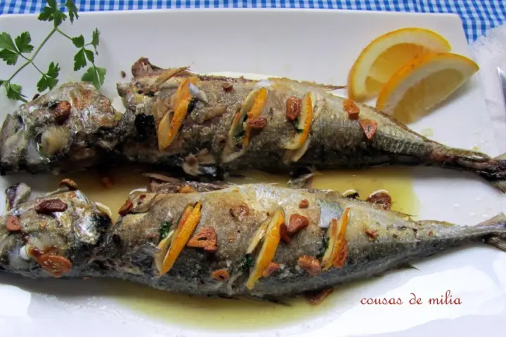 Dos jureles al horno, dorados y jugosos, con rodajas de limón y ajo. Un plato sencillo y delicioso.