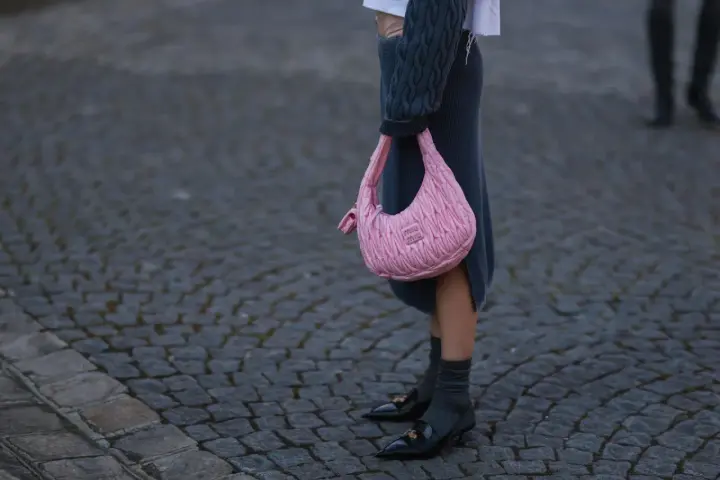 Ein grauer Strickrock kombiniert mit einem Oversize-Pullover und einer pinken Tasche.