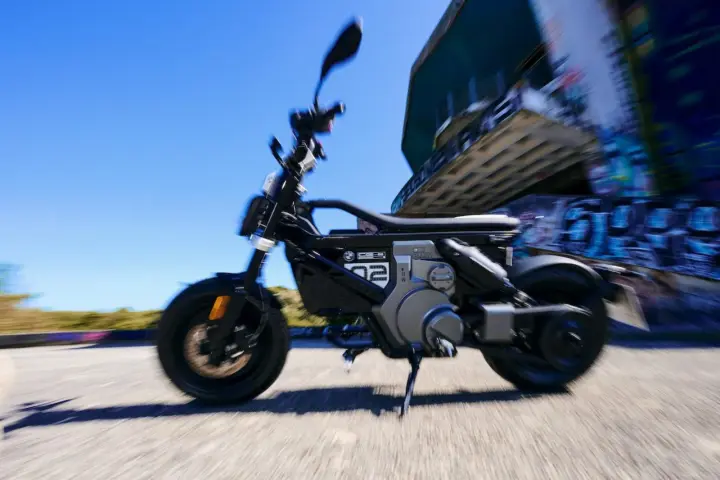 Czarny bmw skuter elektryczny w ruchu, z rozmytym tłem i graffiti.
