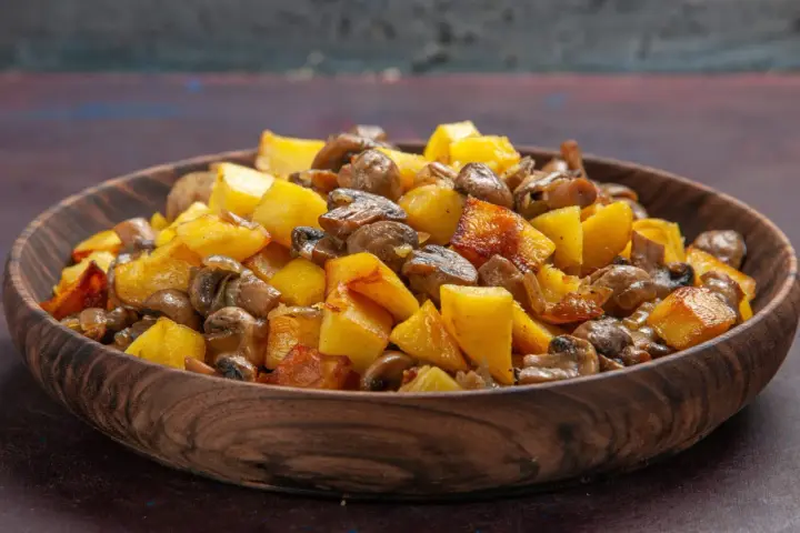 Un delicioso salteado de setas y patatas doradas en un cuenco de madera.