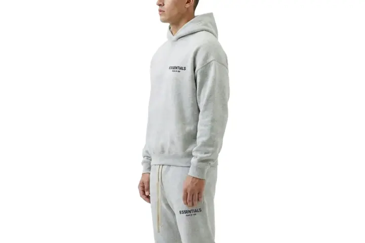 Szary komplet Essentials z kapturem i spodniami dresowymi. Zastanawiasz się, ile waży bluza Essentials? Jest lekka i wygodna.