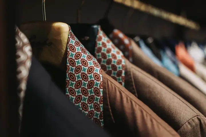 Un guardaroba elegante con giacche marroni e camicie dal tessuto dalle tinte diverse e vivaci, con fantasie geometriche.