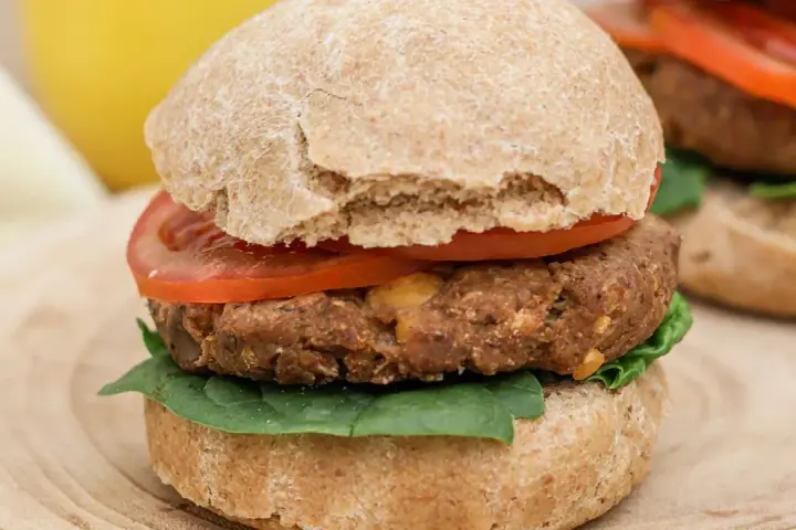 Hamburguesa de legumbres con pan integral, tomate y espinacas.