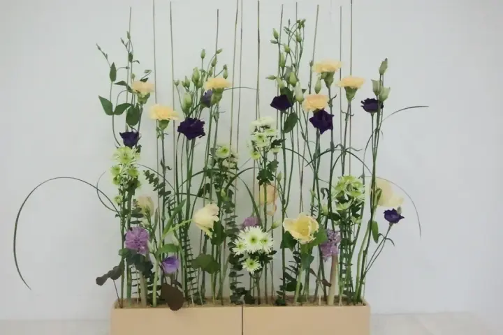 Kwiaty w pastelowych barwach i ciemnofioletowe akcenty, ułożone w stylu wegetatywnym we florystyce, tworzą lekki, naturalny bukiet.