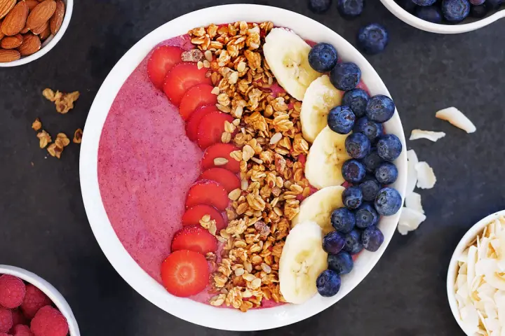 En färgglad acai bowl med jordgubbar, banan, blåbär och granola. Perfekt för en hälsosam frukost eller mellanmål.
