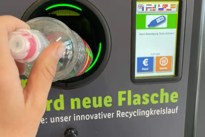 Ręka wrzuca butelkę do automatu. Niemiecki system kaucyjny działa sprawnie, zwracając 0,25 EUR za każdy zwrot.
