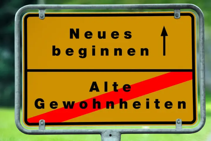 Gelbes Ortsschild: Oben "Neues beginnen" mit Pfeil nach oben, unten "Alte Gewohnheiten" durch roten Balken durchgestrichen. Das Symbol steht für die **passion bedeutung** neuer Wege.