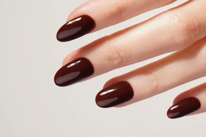 Une idée manucure automne : des ongles courts et arrondis, vernis d'un brun chocolat profond et brillant, évoquant la douceur des feuilles mortes.
