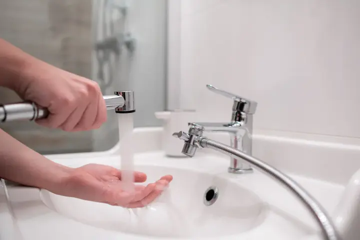 Dłoń pod strumieniem wody z podręcznego bidetu. To proste rozwiązanie do higieny osobistej.