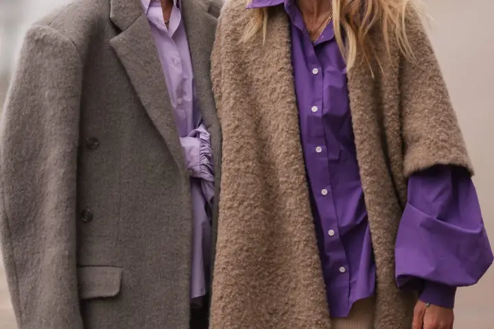 Dos personas con abrigos y camisas moradas. Un ejemplo de que es la fast fashion: ropa barata y de moda rápida.