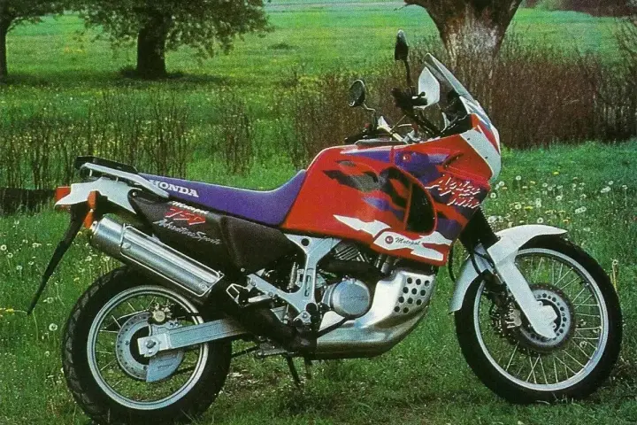 Honda Africa Twin 750 Adventure Sports na tle łąki. Choć to legendarny motocykl, warto znać jego wady przed zakupem.