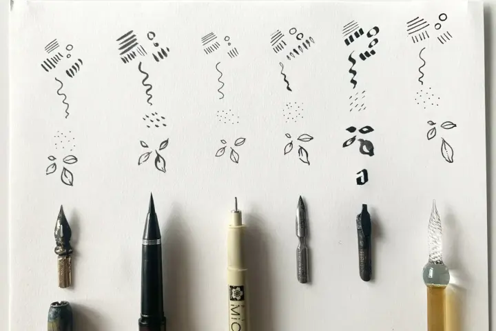 Ejemplos de trazos y formas básicas en dibujos con tinta china, junto a varias plumas y puntas de caligrafía.