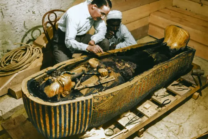 La photo découverte tombeau Toutankhamon : des archéologues examinent la momie dans son sarcophage orné.