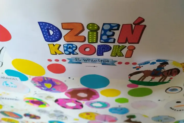 Kolorowa praca plastyczna na Dzień Kropki. Litery "Dzień Kropki" ozdobione kropkami, poniżej rysunki dzieci: konik z jeźdźcem, bałwanek i kolorowe kropki.