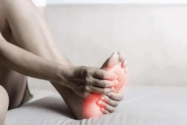A person holds their foot, with red highlights indicating discomfort. This image evokes the feeling of needing natural foot detox.