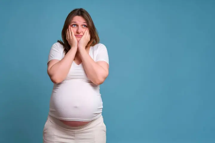 Donna incinta con le mani sul viso esprime paura in gravidanza, preoccupata per il futuro.