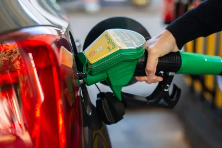 Tankstelle: Eine Hand betankt ein Auto mit dem grünen Zapfhahn. So behältst du im Blick, wie viel verbraucht dein Auto.