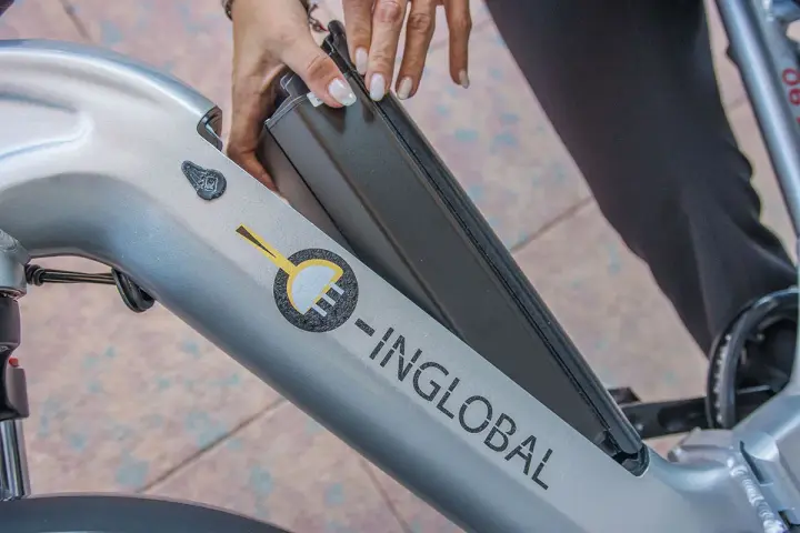 Mani che inseriscono la batteria in una bici elettrica. La durata della batteria di una bici elettrica è fondamentale per l'autonomia.