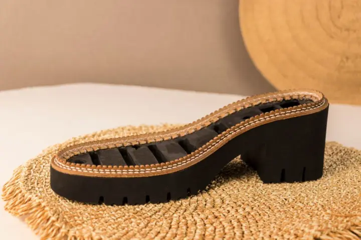 Suela de zapato con plataforma y tacón grueso, elaborada con caucho natural y detalles de cuero.