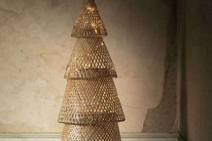 Un sapin de Noël en tissu à faire soi-même, fait de cônes tressés et illuminé de guirlandes lumineuses.