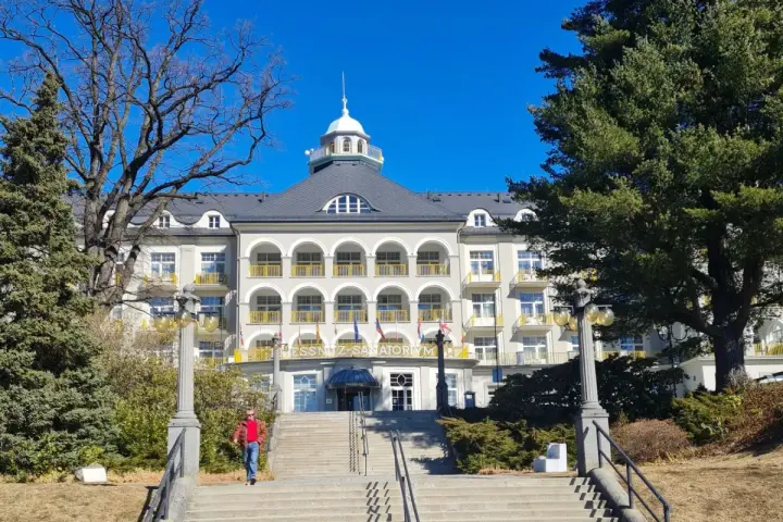 Piękny budynek sanatorium w Jesenikach w Czechach, z charakterystycznymi arkadami i żółtymi balkonami.