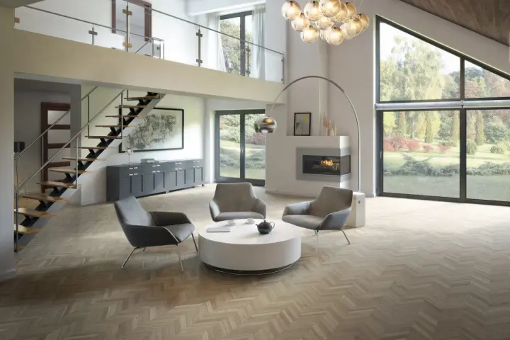 Salon moderne avec un **plafond cathédrale moderne**, escalier flottant, cheminée et grandes baies vitrées donnant sur un jardin.