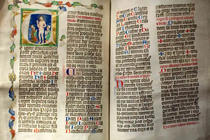First Sunday of Advent readings from an illuminated manuscript. Jesus is depicted in the initial letter, with ornate borders and calligraphy.
