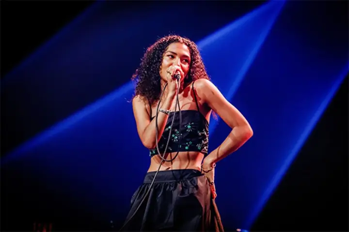 La chanteuse soul française, avec sa voix envoûtante, captive le public sous les projecteurs bleus.