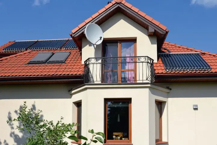 Nowoczesny wykusz w domu z balkonem i oknami, na dachu panele słoneczne i antenę satelitarną.