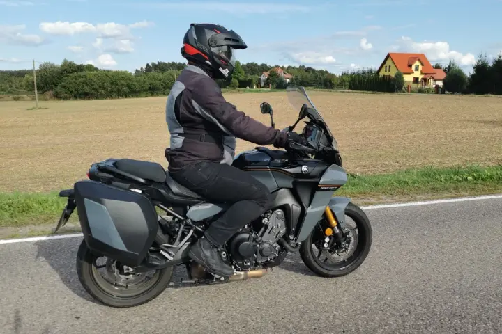 Motocyklista na Yamaha Tracer 900, z sakwami, w kasku, jedzie po drodze. Dane techniczne tego modelu są imponujące.