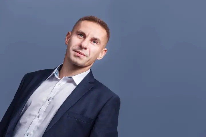 Mężczyzna w garniturze i białej koszuli, patrzący w górę.