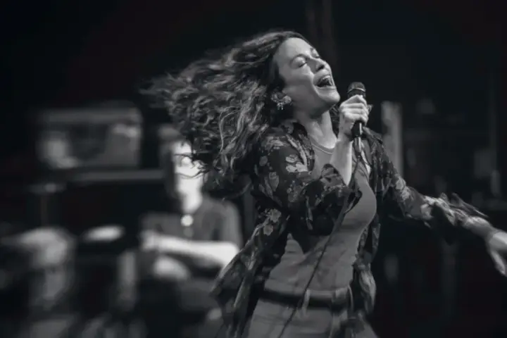 Energetyczny alanis morissette koncert, wokalistka śpiewa z pasją, włosy rozwiane w locie.